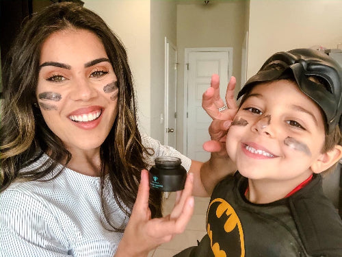 woman and child with stripes of olecea charcoal mask on their faces