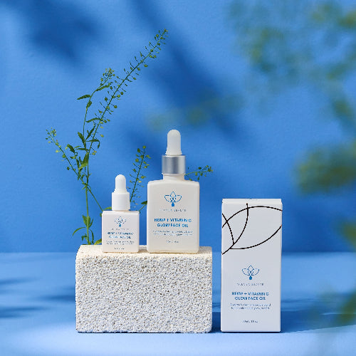 two bottles of olecea hemp vitamin c oil on white stone with box and blue background