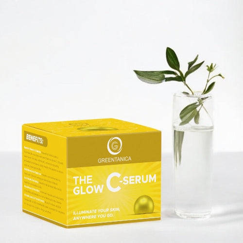 Greentanica The Glow C-Serum yellow product box displayed next to a clear glass vase containing water and a green leafy stem, on a clean white background.