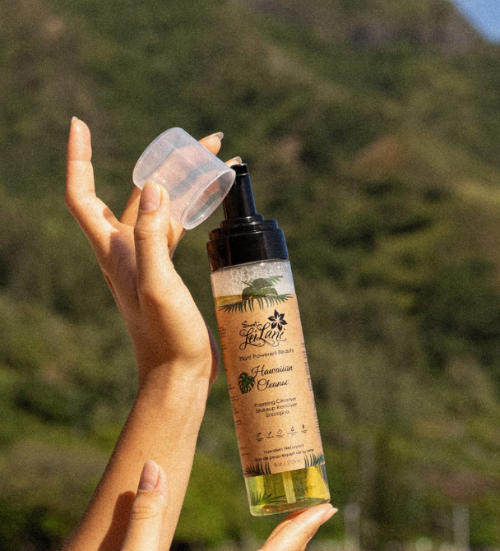 Hand holding a bottle of Australian Cypress essential oil with a scenic background