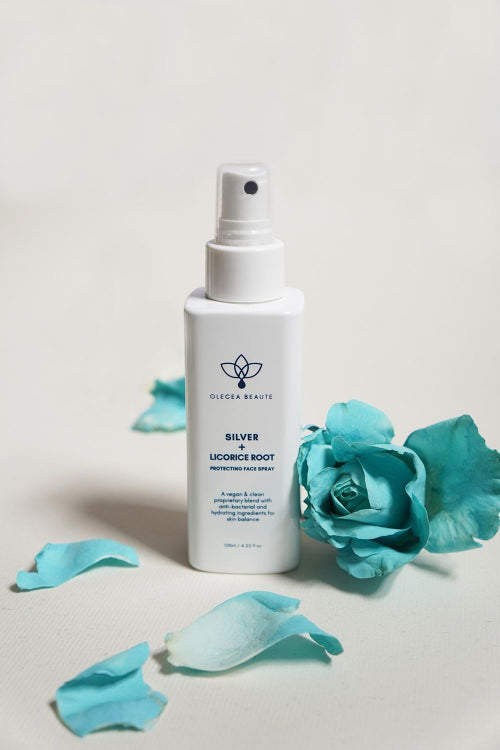A white spray bottle labeled Silver + Licorice Root Protective Facial Spray by Olecea, indicating it is a skincare product.