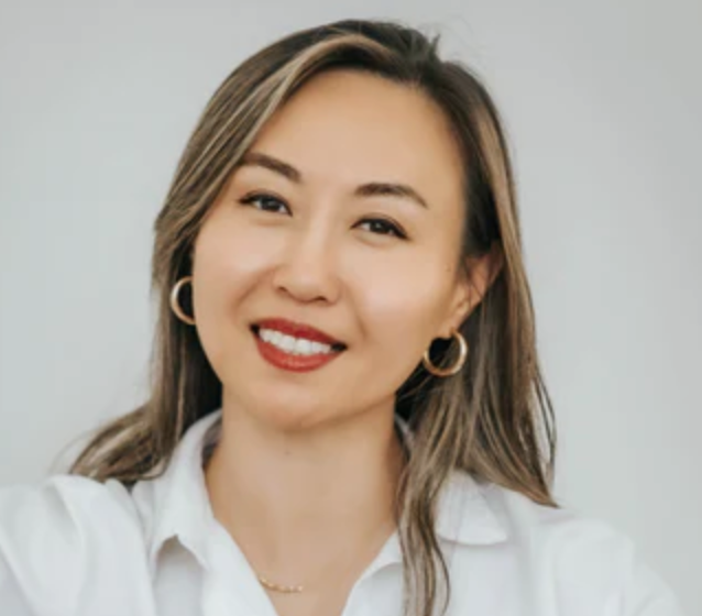 Person with long hair smiling against a plain background