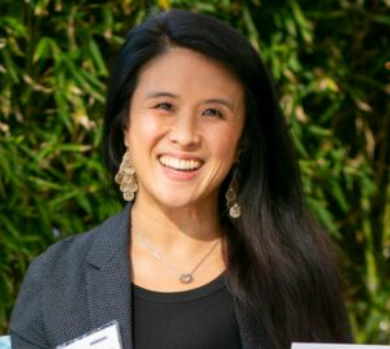 Belinda smiling outdoors with greenery in the background