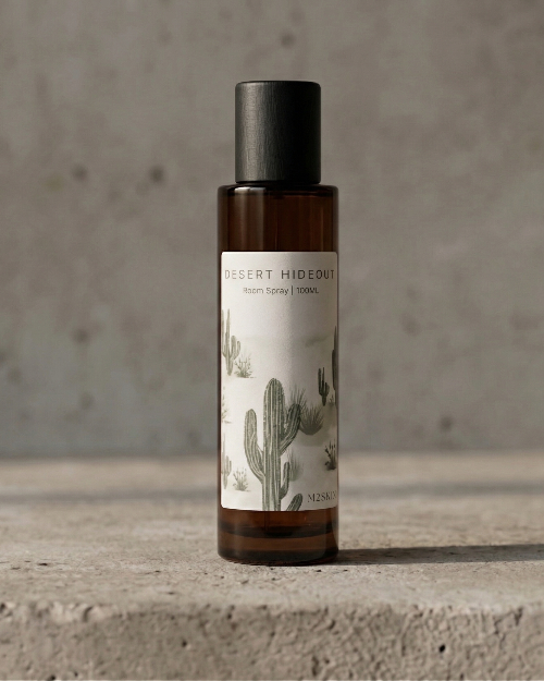 Bottle of 'Desert Hideout' product with cactus design on label against a concrete background