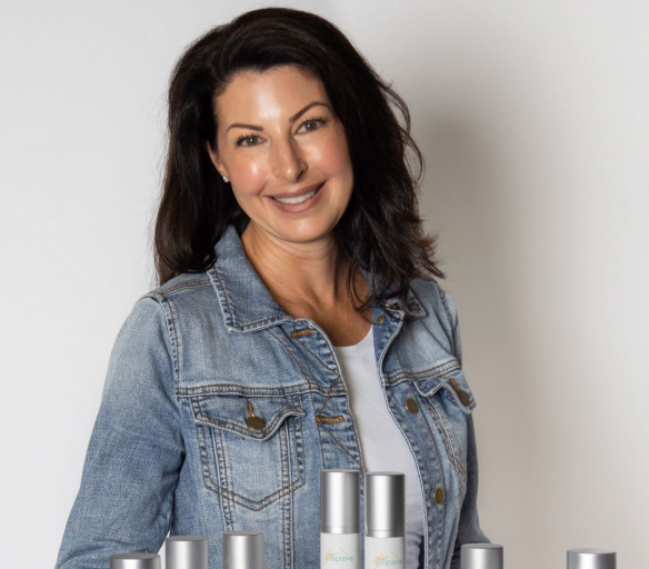 Jamie standing behind skincare products on a neutral background