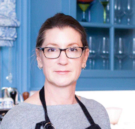 Person wearing glasses and an apron in a kitchen setting.