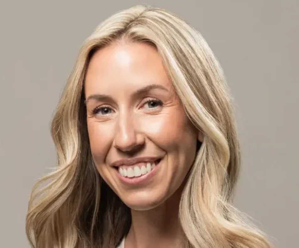Woman with blonde hair smiling against a gray background