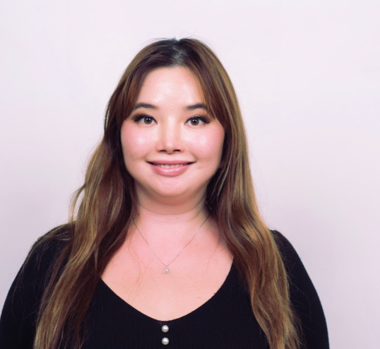 Tugs with long hair wearing a black top against a plain background