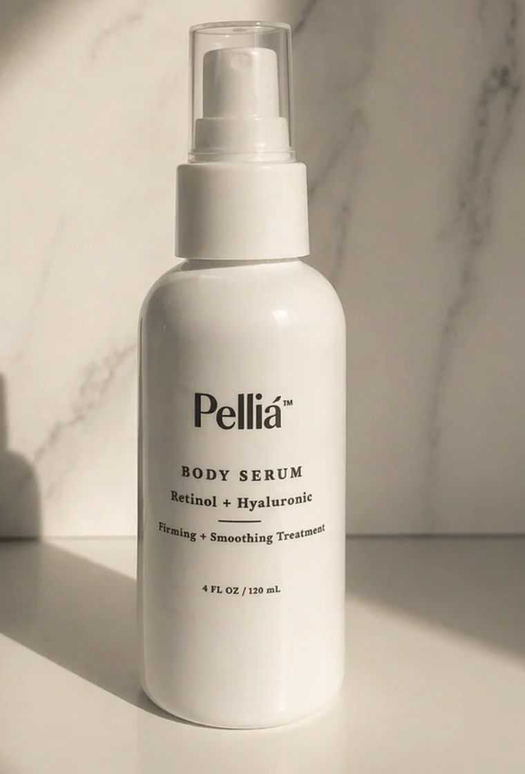 A white pump bottle of Pellía Body Serum with Retinol + Hyaluronic, set against a light marble background with dramatic side lighting.