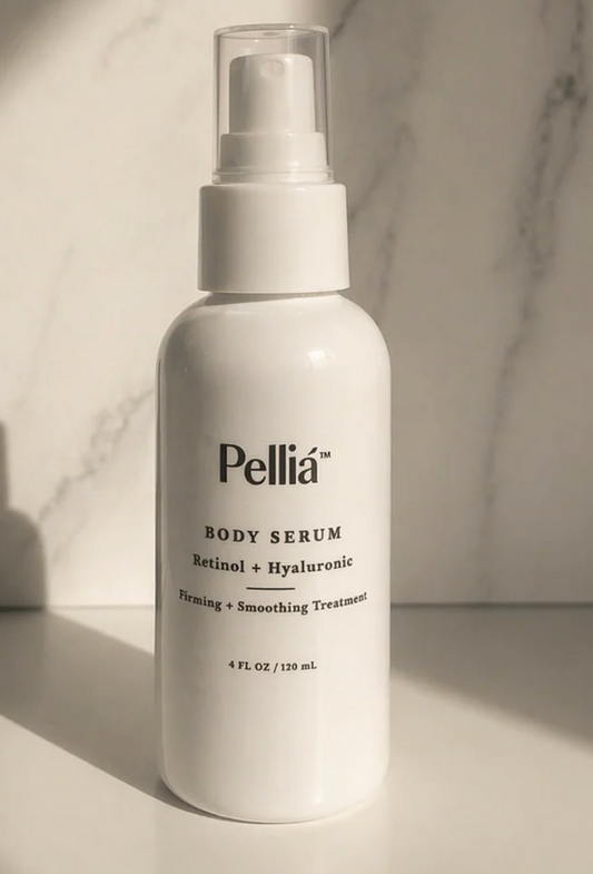A white pump bottle of Pellía Body Serum with Retinol + Hyaluronic, set against a light marble background with dramatic side lighting.