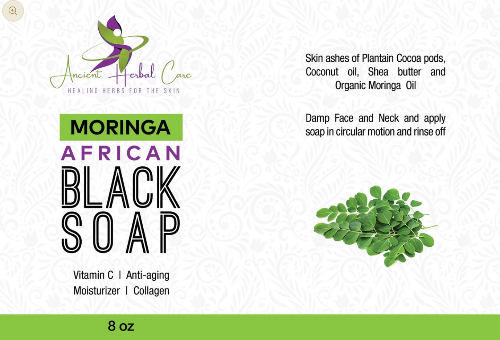 Front of a 8 oz box of Ancient Herbal Care Moringa African Black Soap, featuring product details, ingredients, and a small photo of fresh green moringa leaves on a white background with a green bottom band.