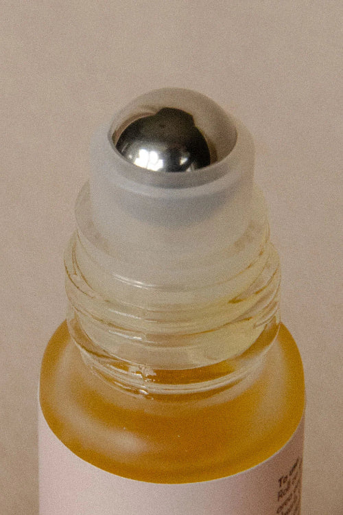 Close-up of a small glass bottle with a metal cap on a beige background