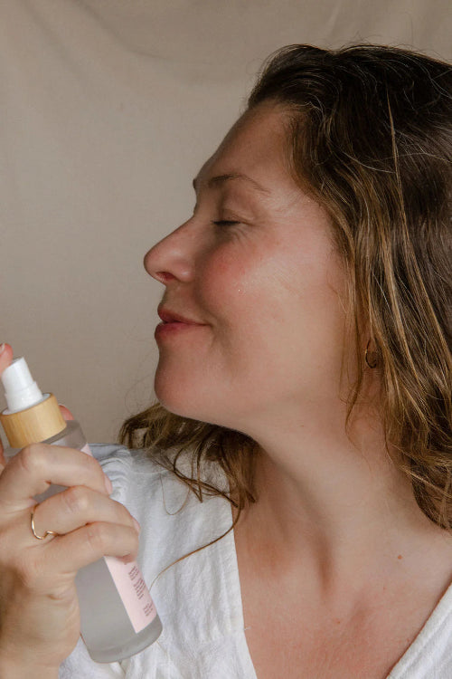Woman holding a spray bottle with a neutral background
